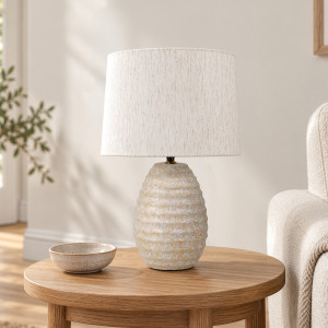 Lopez ceramic lamp on a round timber side table beside a cream armchair in a neutral living room