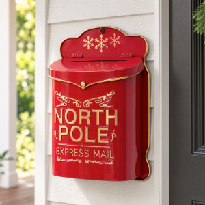 Red and gold North Pole Christmas Postbox mounted on white weatherboards beside a dark front door