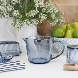 Soft blue glass measuring jug with curved handle, pouring spout and embossed metric and imperial markings