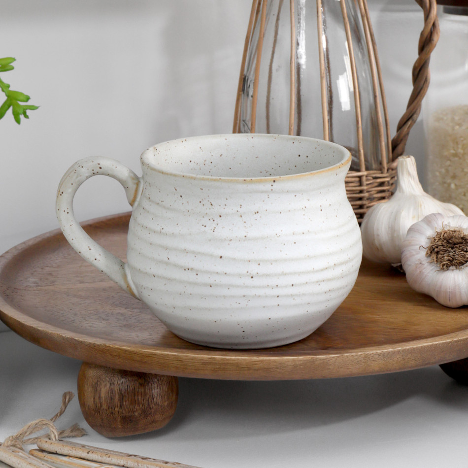 Speckled off-white ribbed ceramic mug styled on a raised wooden board