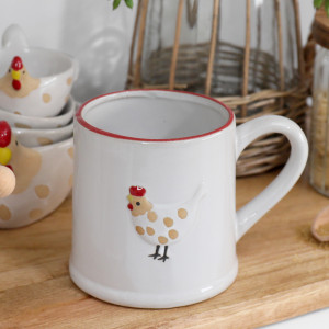 Front view of the white ceramic hen mug with red rim, curved handle and spotted chicken detail