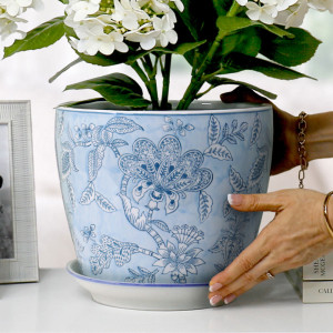 Close-up of hands positioning the Swanson Blue Lace plant pot and saucer with white hydrangeas