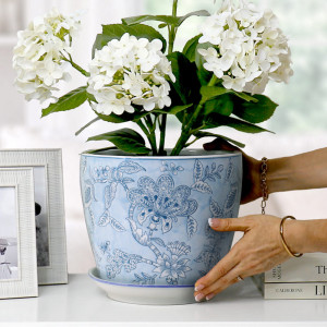 Swanson Blue Lace plant pot with white hydrangeas on a white console beside silver photo frames and books