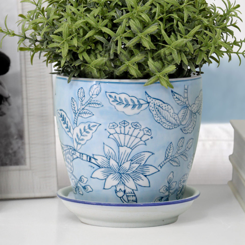 Close-up of a pale blue floral ceramic plant pot and white saucer filled with narrow green foliage