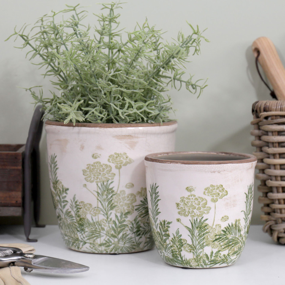 Large Glendale rounded pot with foliage behind the smaller matching pot, beside gardening tools and a woven basket