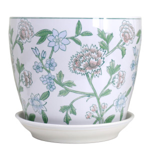 Large white ceramic plant pot with pink and blue flowers, green leaves and a matching white saucer