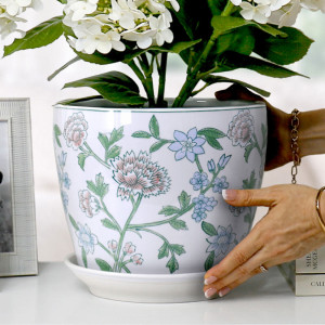 Close-up of hands positioning the Spring Flowers plant pot and saucer with white hydrangeas