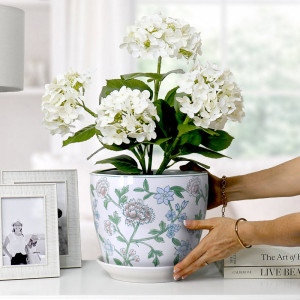 Spring Flowers plant pot with white hydrangeas on a white console beside silver photo frames and books