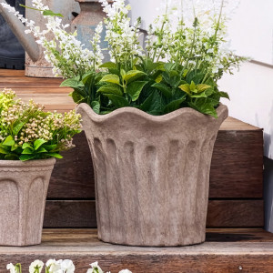 Large sand terracotta fluted plant pot filled with white flowers on wooden steps