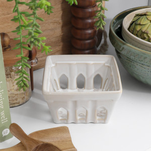 Cream ceramic berry punnet with cutout sides styled on a kitchen bench beside bowls and wood accessories