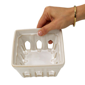 Front view of an empty cream ceramic berry washer with square rim, fluted sides and drainage cutouts