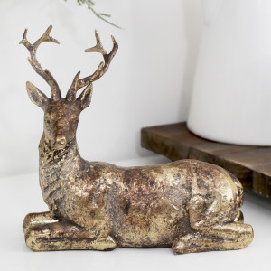 Close-up of resting reindeer with its head on the left, showing branching antlers and distressed gold finish