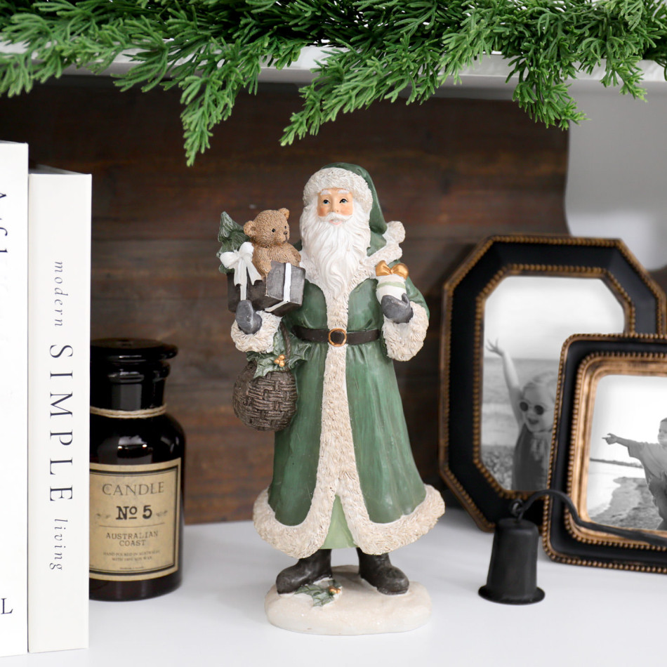 St Nicholas with Bear Christmas decoration on a white shelf with books, a candle and family photos beneath greenery