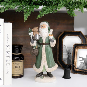 St Nicholas with Bear Christmas decoration on a white shelf with books, a candle and family photos beneath greenery