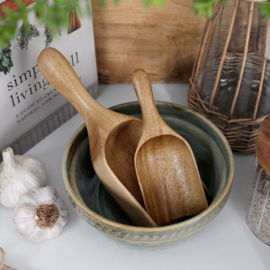 Small and large acacia wood scoops arranged together in a green ceramic bowl.