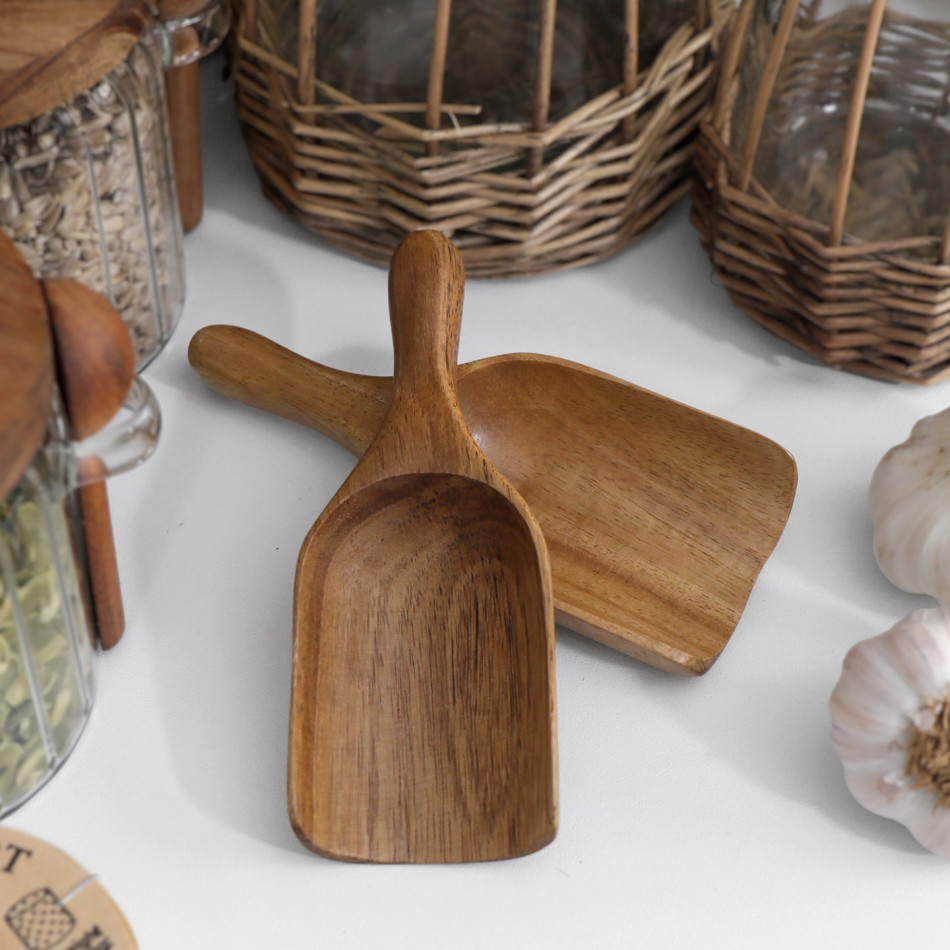 Small acacia wood scoops displayed with pantry jars in a styled kitchen setting.