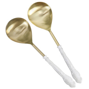 Set of two gold-toned stainless steel serving spoons with white enamel handles on a white background