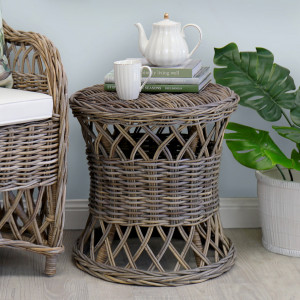 woven rattan side table styled with a teapot, cup and books beside an armchair