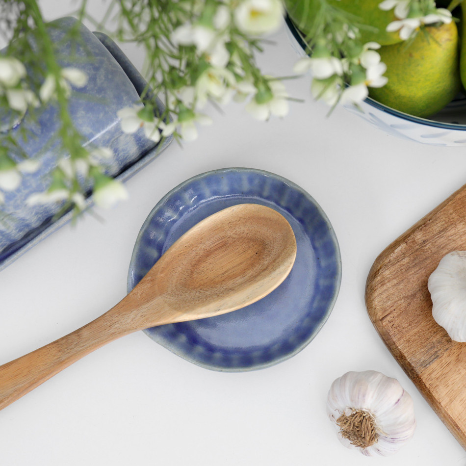 Blue ceramic spoon rest with gently fluted rim styled on a white kitchen bench