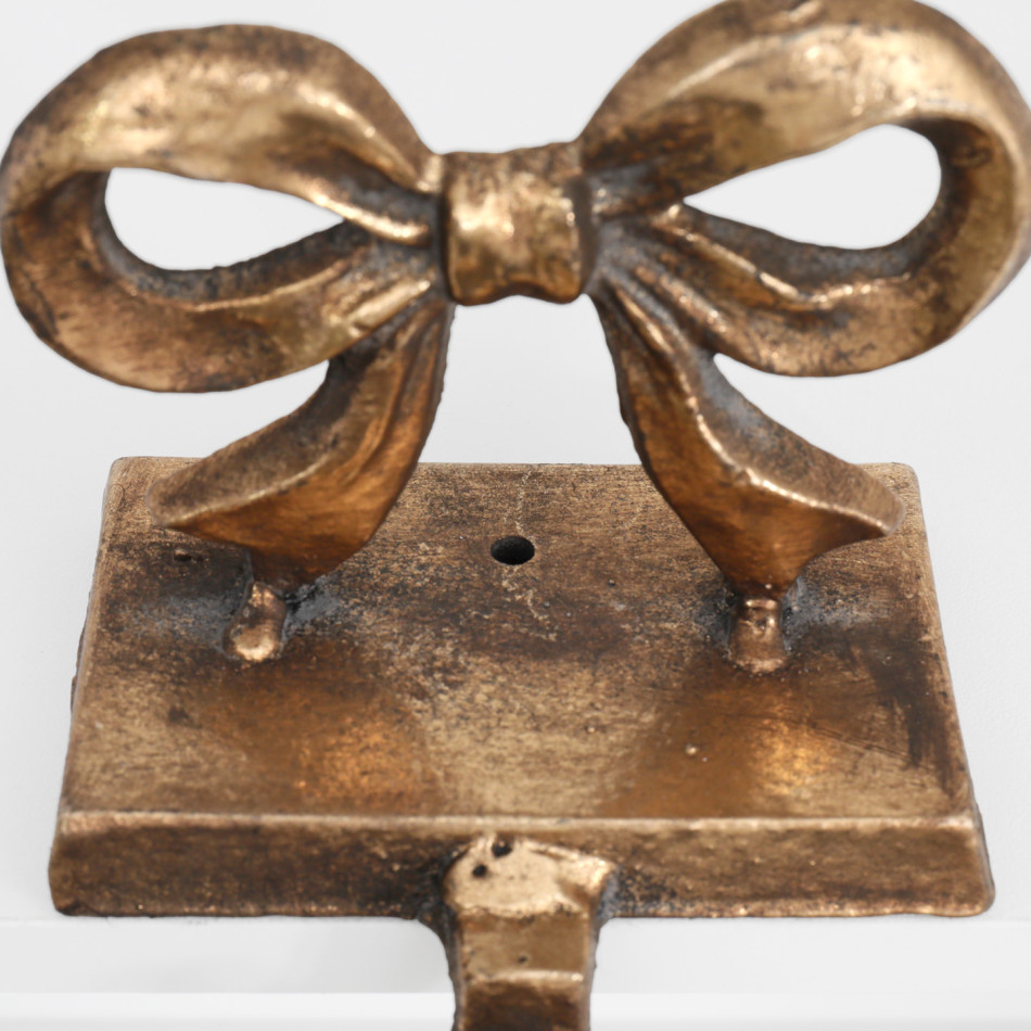 Close-up of the screw hole in the base of Clara gold bow stocking hook.