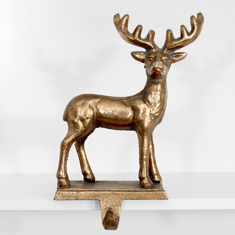 Front view of the gold reindeer figure and curved stocking hook on a white shelf