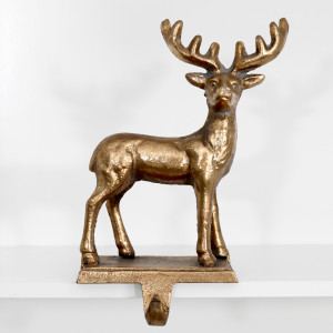Front view of the gold reindeer figure and curved stocking hook on a white shelf