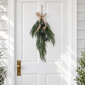 Glad Tidings Green Bell Christmas Swag hanging on a white panelled door with brass door hardware.