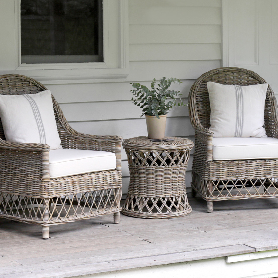 Clifton rattan side table positioned between two matching cushioned armchairs