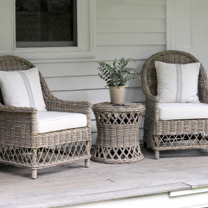 Clifton rattan side table positioned between two matching cushioned armchairs