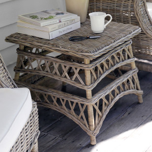 Antique-grey square rattan side table with lattice base styled with books and a white cup