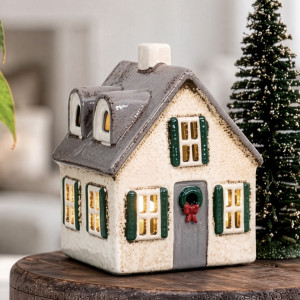 Close-up of ceramic Christmas house tealight holder with grey roof, green shutters and a wreath on the door