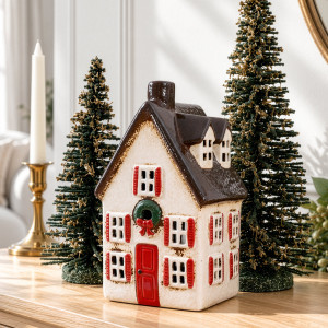 Cream Christmas house tealight holder with red door and shutters, displayed between green decorative trees
