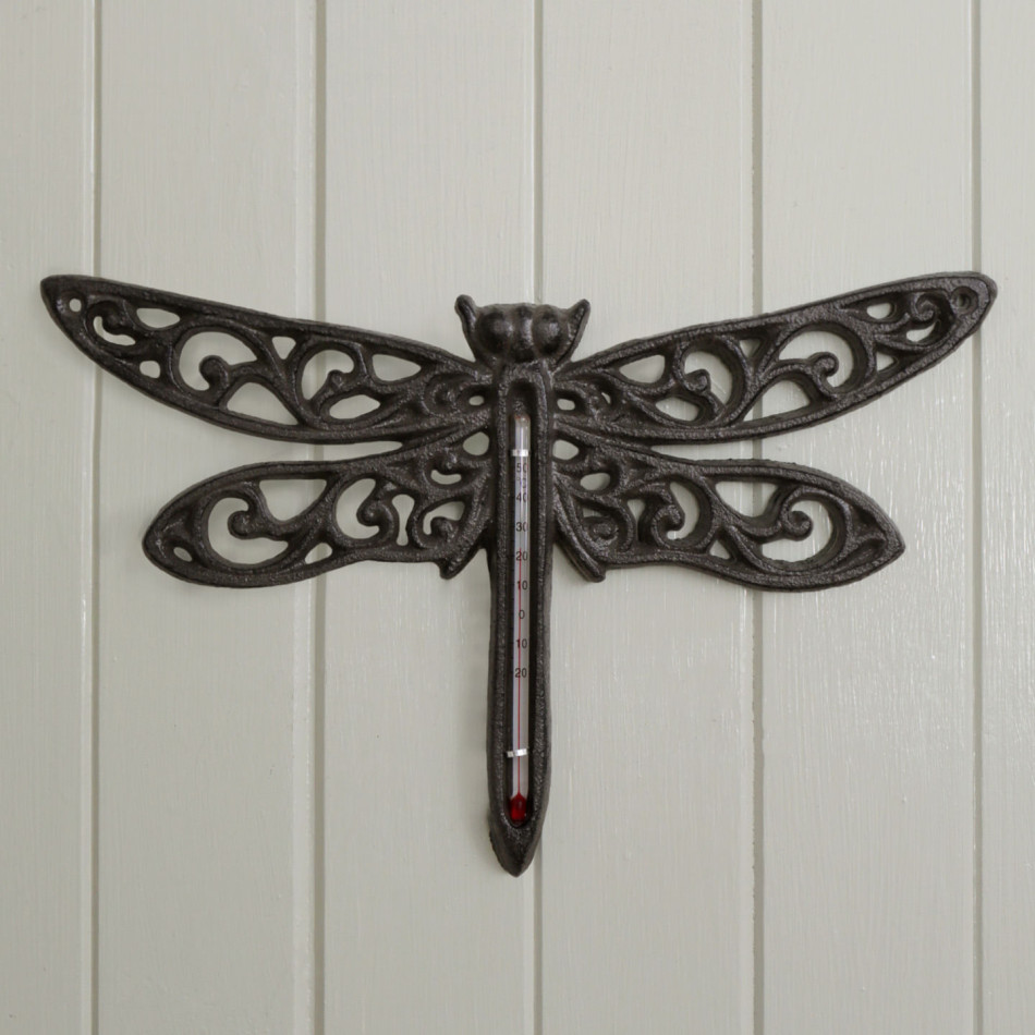 Dark brown cast iron dragonfly wall thermometer mounted on pale timber panelling