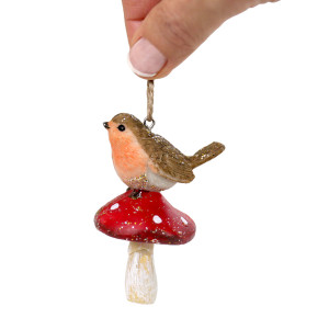 Robin on toadstool Christmas decoration held by its hanging loop against a white background