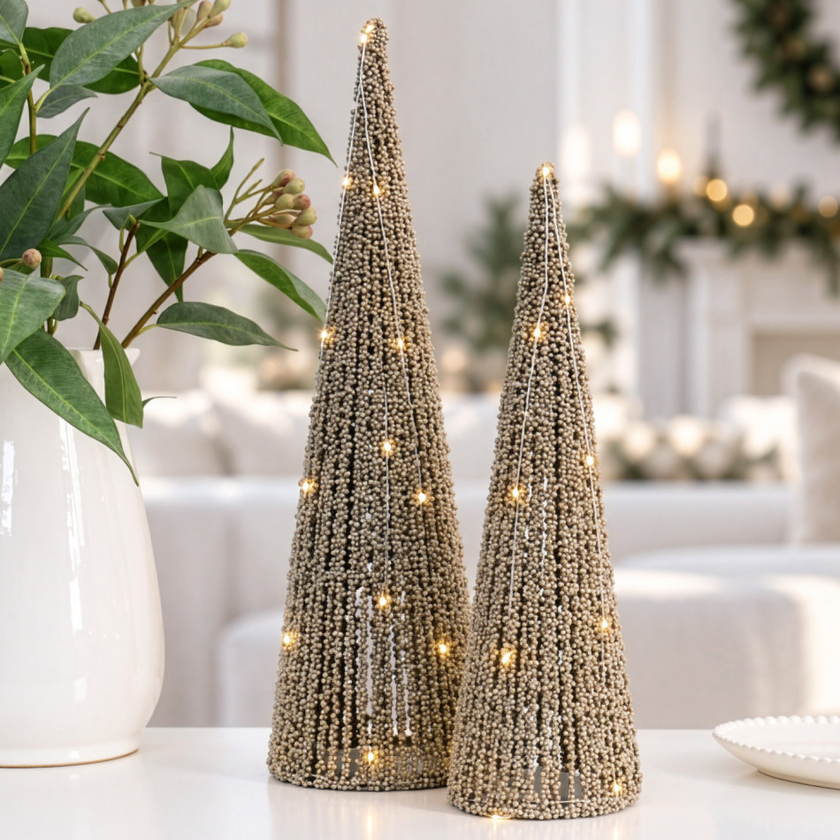 Large and small champagne-gold beaded Christmas trees with LED lights beside eucalyptus in a white vase