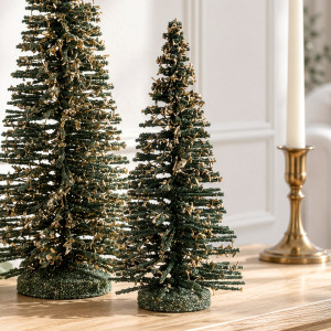 Small Winter Noel tree with gold branch accents beside the coordinating large tree and a gold candle holder