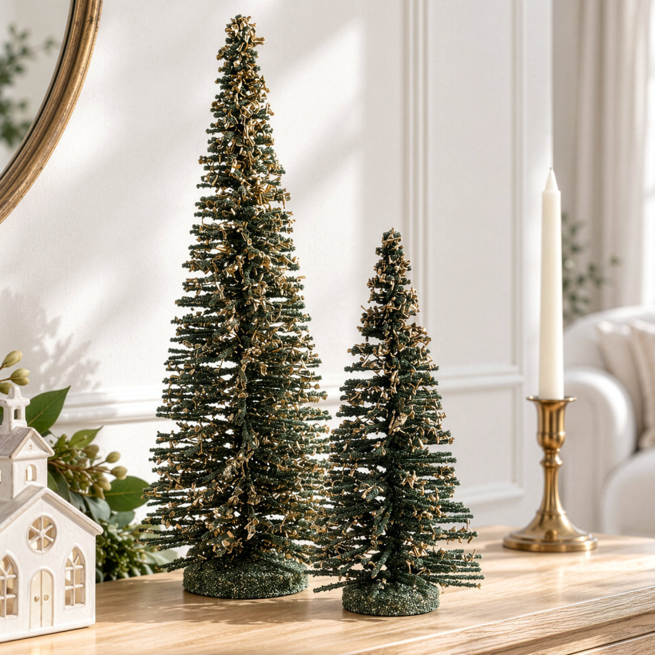 Large and small dark green Winter Noel trees with gold accents displayed beside a white church and gold candle holder