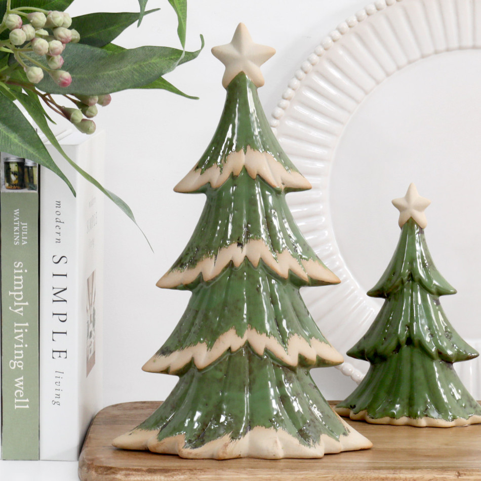 Large green ceramic Christmas tree with cream branch edges and star, styled on a wooden board beside books and the smaller tree.