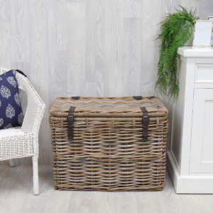 Rochester rattan storage trunk displayed beside a white chair and cabinet