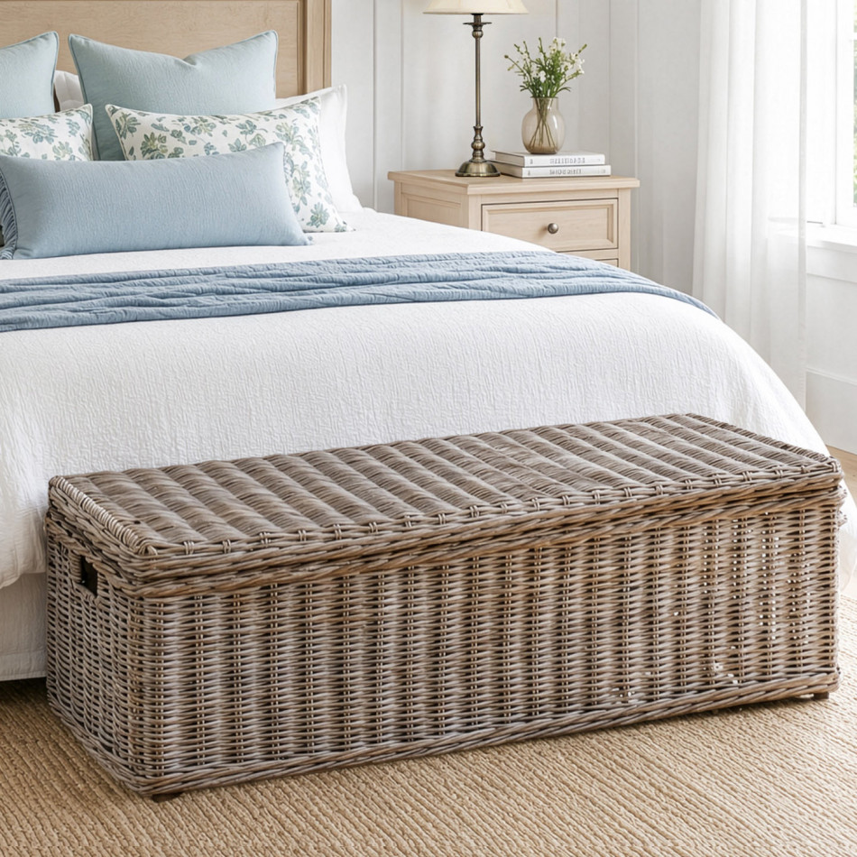 Long antique grey rattan trunk at the foot of a blue and white bed