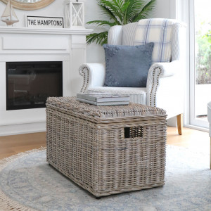 Closed greywash rattan trunk styled beside an armchair and fireplace