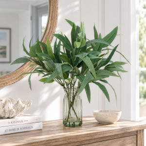 Artificial eucalyptus arrangement in a faceted glass vase styled beneath a round mirror