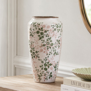 Tall Evergreen floral vase styled on a timber console beside stacked books and a round mirror