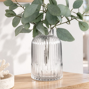 Clear ribbed glass vase with eucalyptus styled on a pale wood console