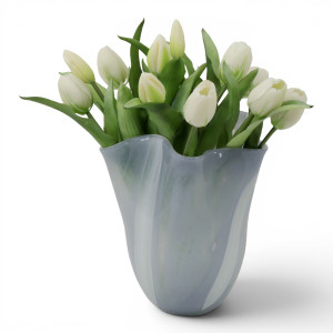 Sculptural sea grey glass vase holding a full arrangement of white tulips