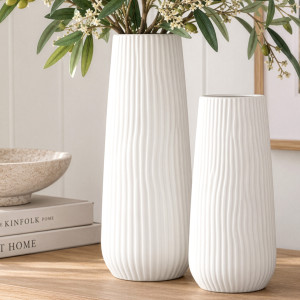 Tall Zahra ribbed white vase with leafy stems beside the smaller matching vase on a timber surface