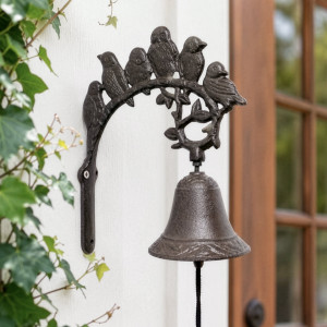 Rustic dark brown cast iron bird wall bell mounted beside a timber-framed doorway
