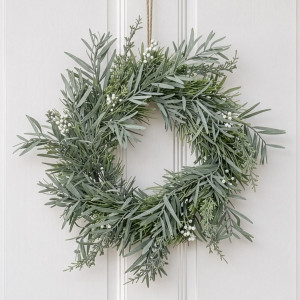 Mixed silver green foliage wreath with white berry accents hanging by twine against white panelling.