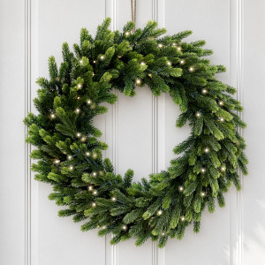 Forest Glow light-up green pine Christmas wreath hanging on a white panelled door with a brass handle